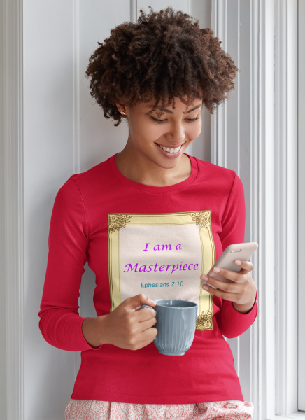 Woman  wearing red long sleeve shirt with the "I am a Masterpiece" Design on the front with a gold frame. She is checking her cell phone and holding a coffee mug.