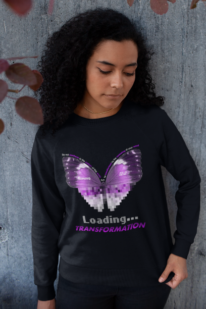 Woman wearing black crewneck sweater with a purple butterfly on front Romans 12:2 is on the butterfly. "Loading ... Transformation" is under the Butterfly in silver and purple letters.